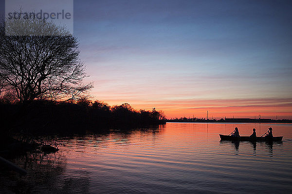 Silhouette von Frauen im Ruderboot auf dem See gegen den Himmel bei Sonnenuntergang