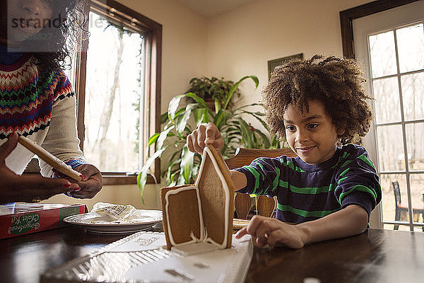 Mutter und Sohn machen Lebkuchenhaus zu Hause