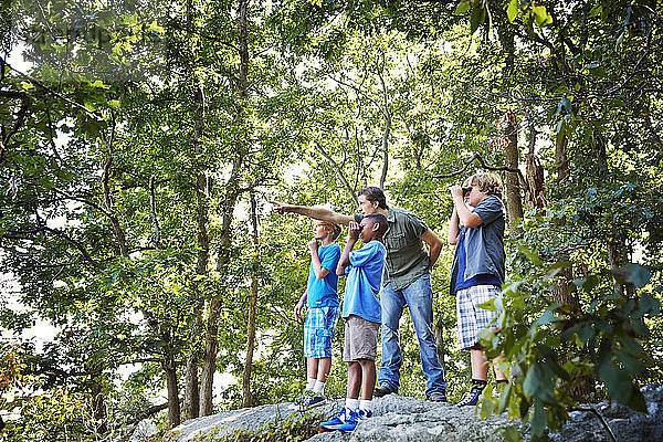 Lehrer erklärt den Schülern  wie sie während einer Exkursion auf Felsen im Wald stehen