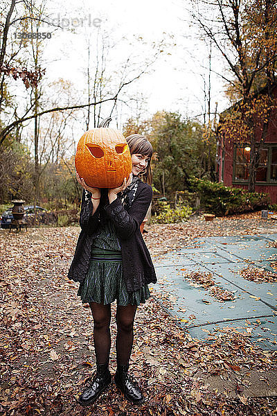 Frau trägt Halloween-Kürbis  während sie auf dem Feld steht