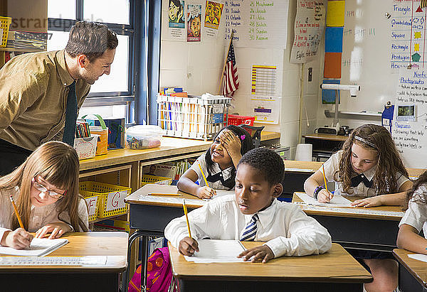 Lehrer spricht mit Schüler während der Unterrichtsstunde im Klassenzimmer