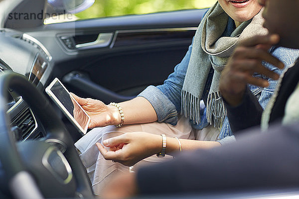 Frau zeigt Mann Tablet-Computer  während sie im Auto sitzt