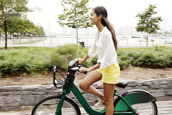 Glückliche Frau fährt Fahrrad auf der Straße in der Stadt