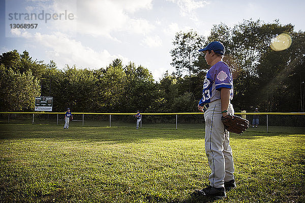 Seitenansicht eines Jungen  der auf dem Spielfeld Baseball spielt