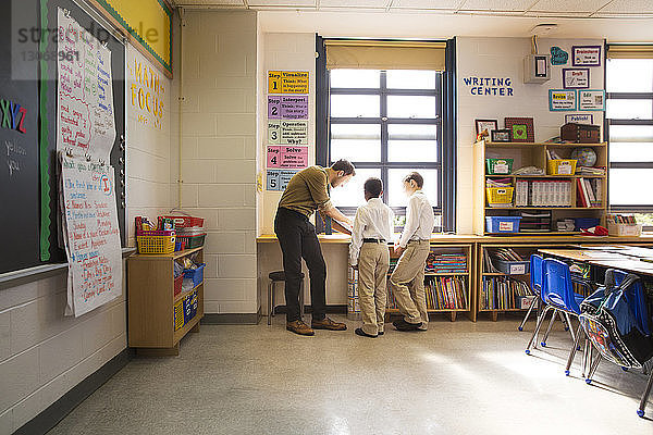 Lehrer spricht mit Jungen  während er im Klassenzimmer steht