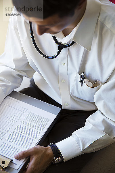 Hochwinkelansicht eines Arztes beim Lesen eines Dokuments