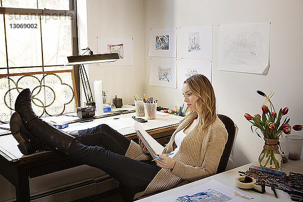 Frau hält Notizblock und Stift  während sie im Kunstatelier sitzt