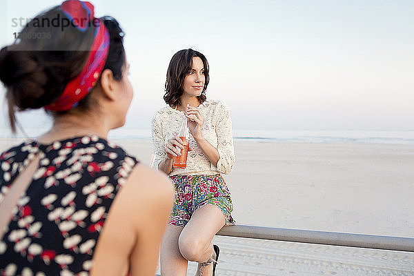 Rückansicht einer Frau mit Freundin am Pier am Strand