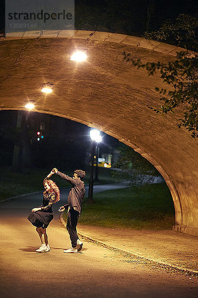 Glückliches Paar tanzt nachts auf der Straße