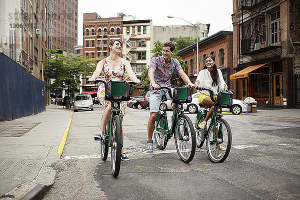 Glückliche Freunde fahren Fahrrad auf der Straße