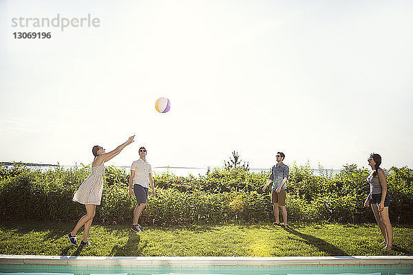 Fröhliche Freunde spielen mit dem Ball im Hinterhof gegen den Himmel