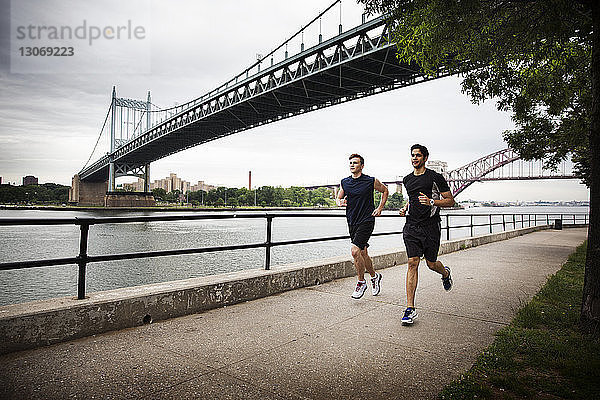 Freunde rennen auf der Promenade gegen die Triborough-Brücke