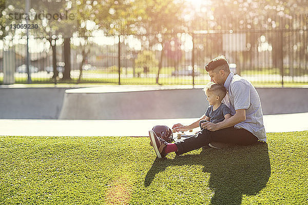 Vater und Sohn sitzen auf einem Grasfeld
