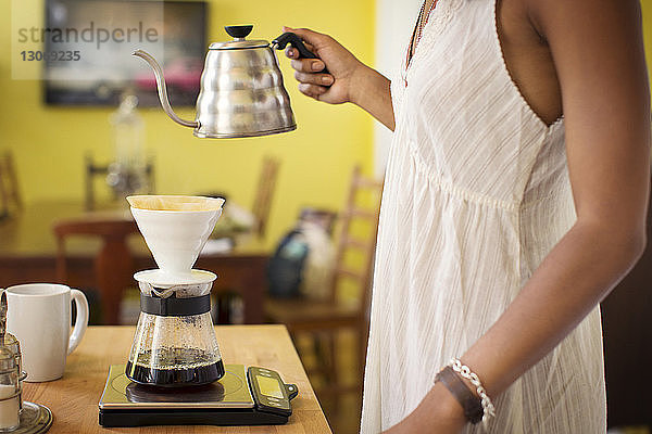 Seitenansicht einer Frau  die zu Hause Kaffee kocht