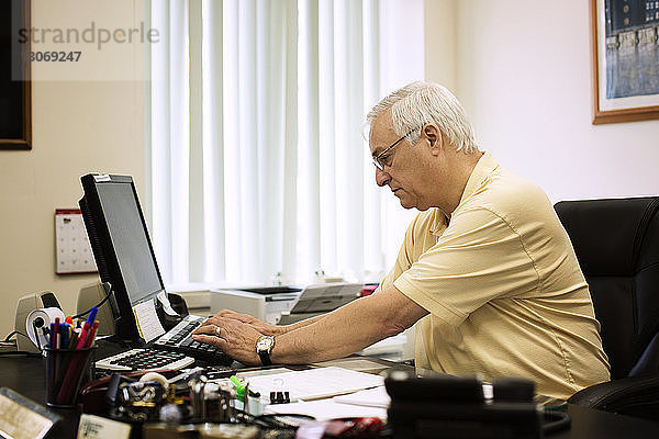 Geschäftsmann  der am Desktop-Computer im Büro arbeitet