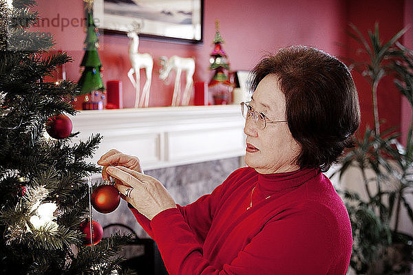 Frau schmückt den Weihnachtsbaum zu Hause