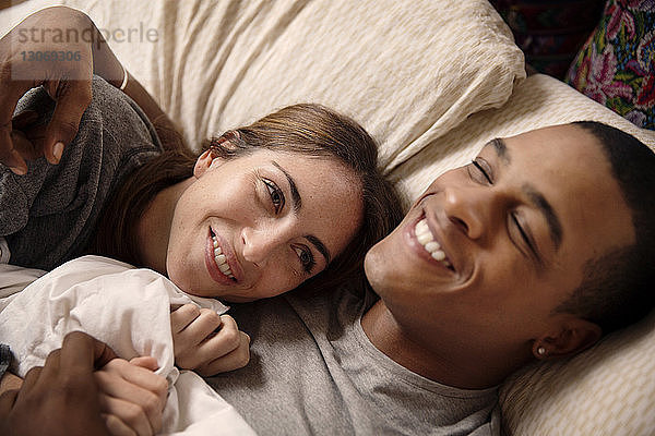 Lächelndes Paar liegt zu Hause auf dem Bett