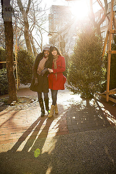 Freunde stehen am Weihnachtsbaum auf dem Fußweg