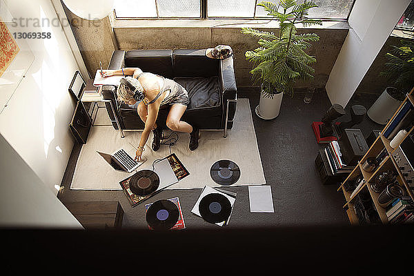 Hochwinkelansicht eines Musikers mit Laptop bei der Arbeit zu Hause