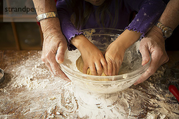 Ausgeschnittenes Bild eines Mädchens mit Großmutter  die Teig knetet  während sie Kekse backt