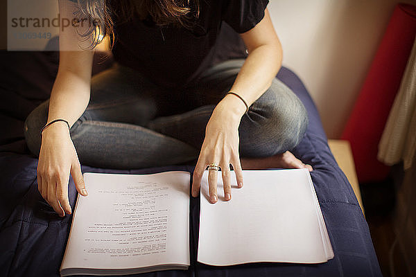 Niedriger Abschnitt einer Frau  die zu Hause im Bett ein Buch liest