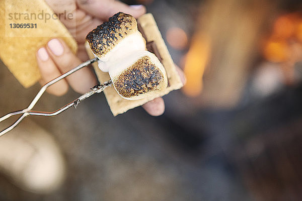 Beschnittenes Bild von Händen  die Marshmallow mit einer Gabel über Smores halten