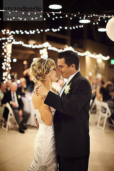 Braut und Bräutigam tanzen während der Hochzeit im beleuchteten Raum