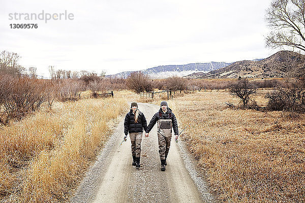 Paar hält sich beim Gehen auf dem Fußweg an den Händen