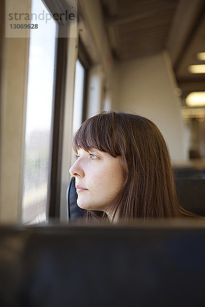 Nachdenkliche Frau schaut weg  während sie im Zug reist