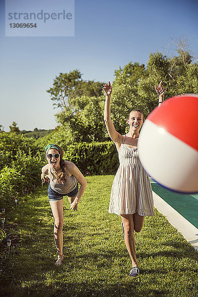 Fröhliche Freunde spielen an einem sonnigen Tag mit dem Ball im Hinterhof