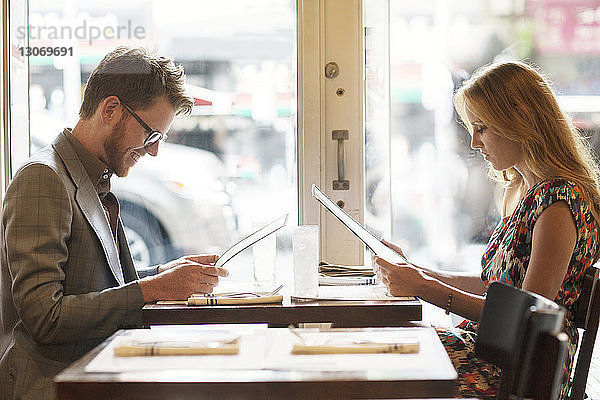 Seitenansicht des Paares beim Lesen der Speisekarte  während es im Restaurant sitzt