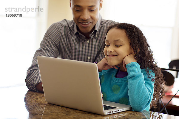 Vater und Tochter benutzen zu Hause einen Laptop