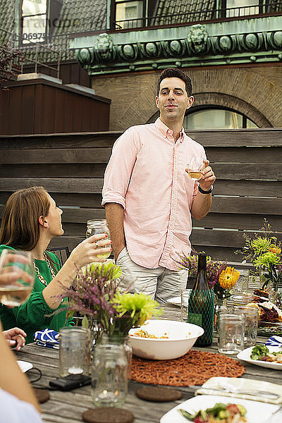 Frau sieht Mann an  der ein Getränk in der Hand hält  während sie am Tisch auf der Terrasse des Gebäudes genießt