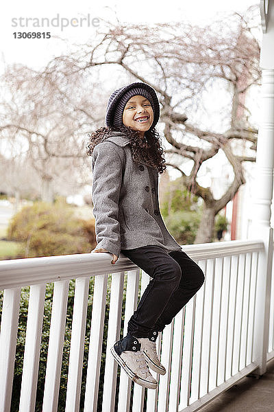 Porträt eines glücklichen Mädchens auf einem Geländer sitzend