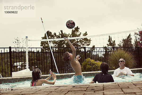 Glückliche Familie beim Volleyballspielen im Pool