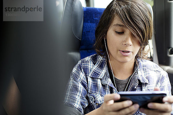 Junge hört Musik auf Tablet-Computer  während er im Bus sitzt