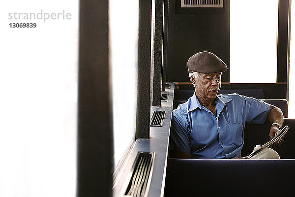 Älterer Mann liest Buch während einer Fährfahrt