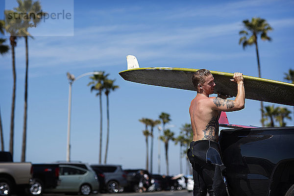 Seitenansicht eines Mannes mit Surfbrett am Strand