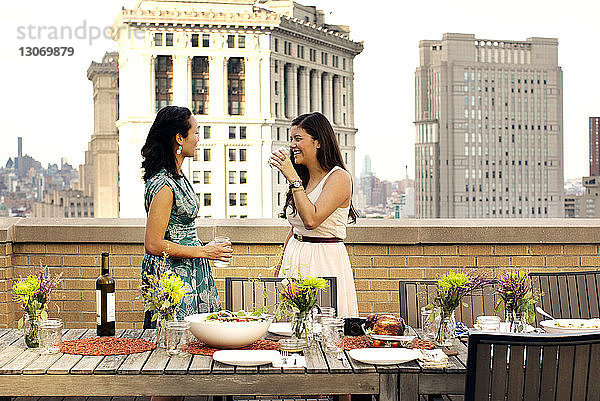 Glückliche Freunde trinken Wein am Tisch auf einer Gebäudeterrasse in der Stadt