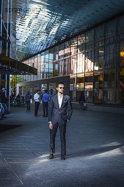 Geschäftsmann steht auf der Straße inmitten moderner Gebäude in der Stadt