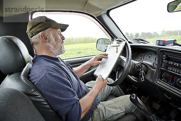 Mann liest  während er im Auto sitzt