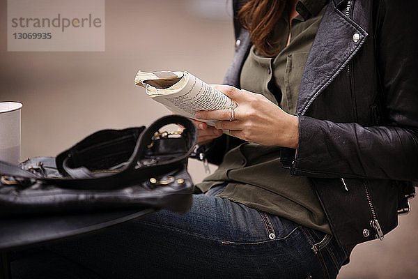 Mittelteil einer Frau  die am Tisch sitzend ein Buch liest