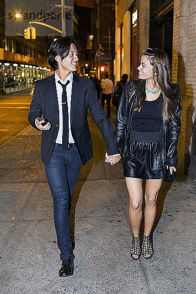 Glückliches Paar schaut sich an  während es nachts auf der Straße der Stadt steht