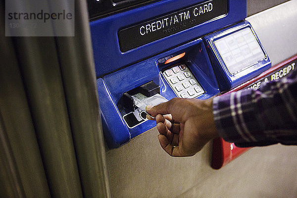 Beschnittenes Bild von Hand beim Einführen der Kreditkarte in den Geldautomaten