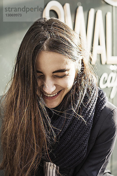 Frau lacht  während sie vor einem Café steht