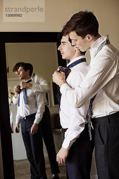 Seitenansicht eines schwulen Mannes  der seinem Freund beim Binden der Krawatte hilft