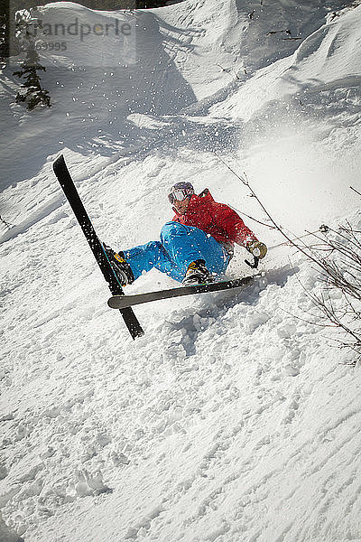 Skifahrer fällt auf schneebedecktes Feld