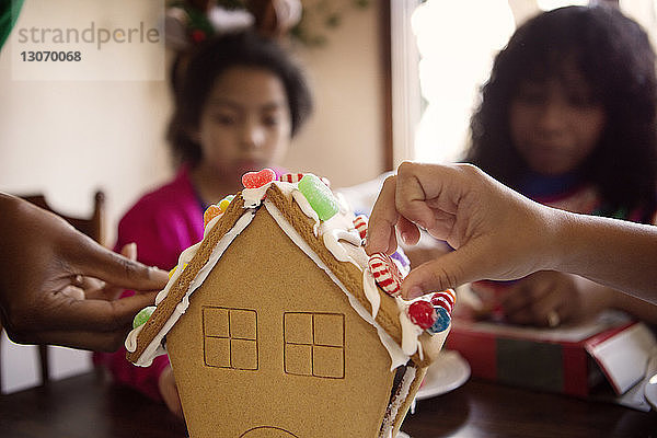 Familie schmückt Lebkuchenhaus zu Hause