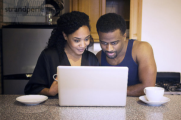Ehepaar betrachtet Laptop-Computer in der Küche