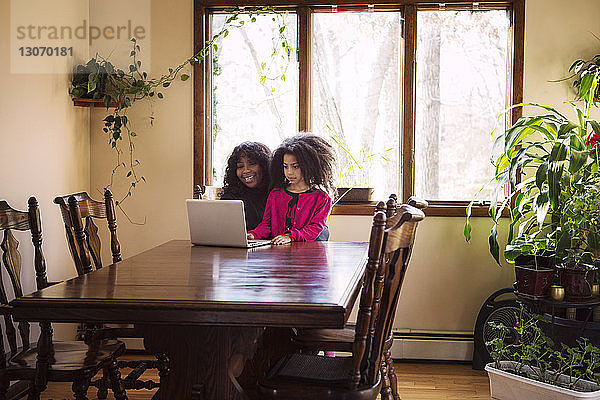 Glückliche Mutter benutzt Laptop mit Tochter zu Hause